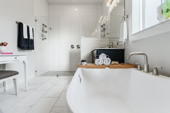 Bathroom featuring marble look tile flooring, a freestanding tub, tiled shower, and vanity | Image 23