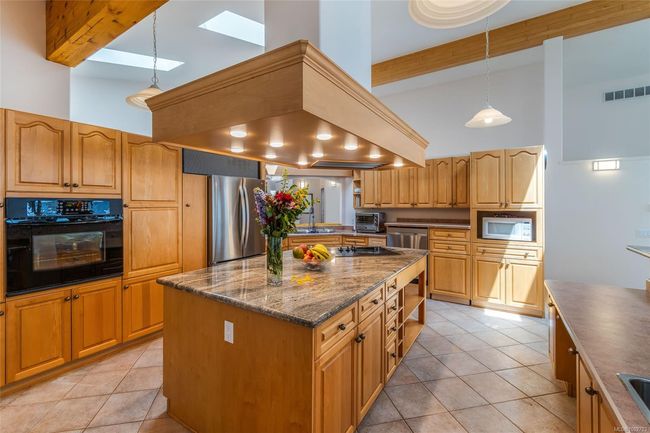 Kitchen featuring stainless steel appliances, high vaulted ceiling, light tile patterned floors, a center island, and a sink | Image 18