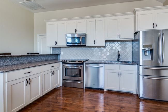 Kitchen featuring a sink, dark wood finished floors, visible vents, and stainless steel appliances | Image 34