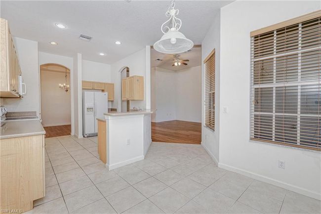 Kitchen featuring light brown cabinetry, white appliances, light tile patterned floors, pendant lighting, and ceiling fan | Image 31