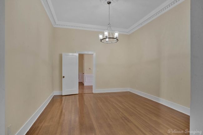 Spare room featuring crown molding, wood finished floors, and a chandelier | Image 8