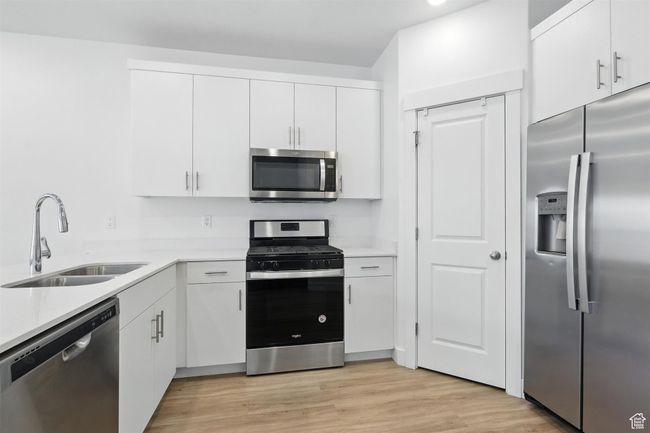 Kitchen featuring stainless steel appliances, light countertops, and white cabinetry | Image 5