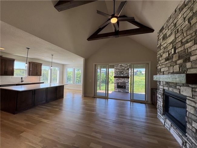 Unfurnished living room featuring a fireplace, beamed ceiling, healthy amount of natural light, wood finished floors, and high vaulted ceiling | Image 6