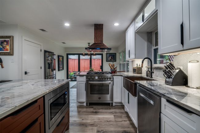Kitchen with stainless steel appliances, island range hood, wood finished floors, recessed lighting, and a peninsula | Image 11