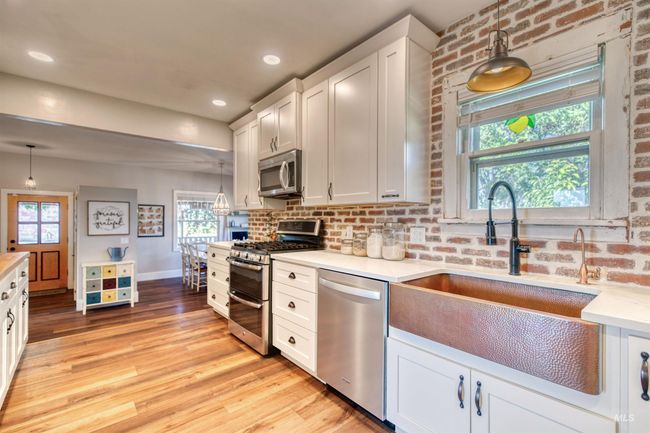 Kitchen with stainless steel appliances, light wood-style floors, white cabinets, pendant lighting, and recessed lighting | Image 9