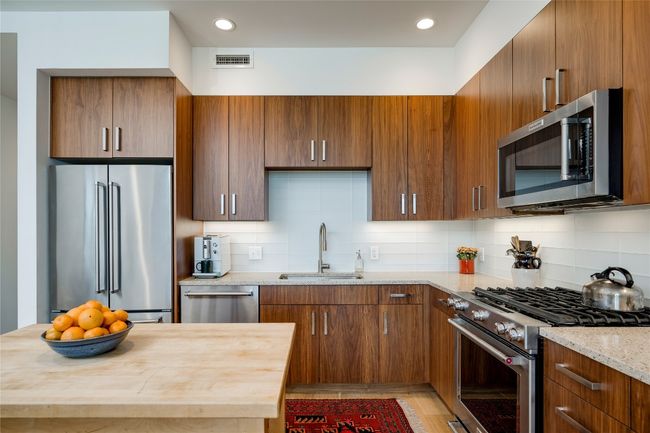 Kitchen featuring appliances with stainless steel finishes, backsplash, light wood-style floors, wooden counters, and brown cabinets | Image 5