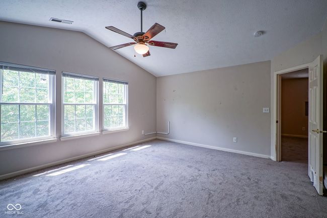 carpeted spare room with ceiling fan, vaulted ceiling, and a textured ceiling | Image 24