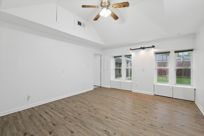 Empty room with healthy amount of natural light, wood finished floors, ceiling fan, and high vaulted ceiling | Image 13