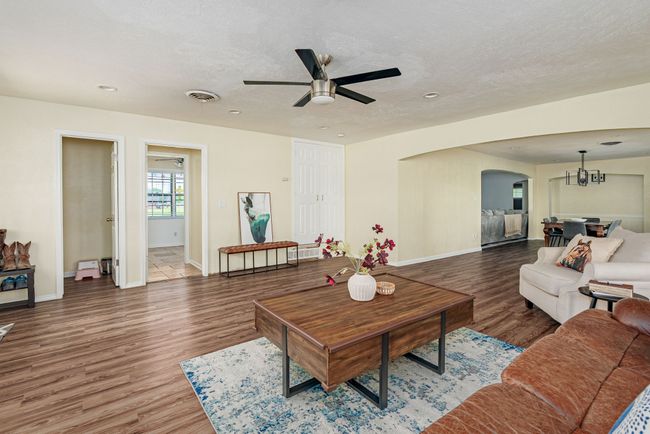 Living area with arched walkways, ceiling fan, wood finished floors, baseboards, and a textured ceiling | Image 22