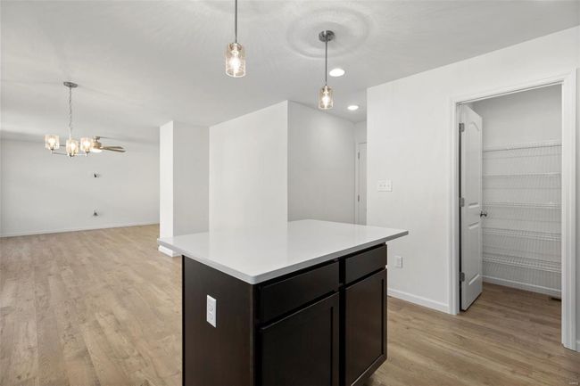 Kitchen featuring decorative light fixtures, a center island, and light hardwood / wood-style flooring | Image 11