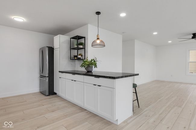 kitchen featuring dark countertops, freestanding refrigerator, white cabinetry, and light wood finished floors | Image 27