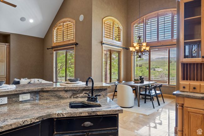 Kitchen with high vaulted ceiling, a sink, healthy amount of natural light, a chandelier, and light stone countertops | Image 29