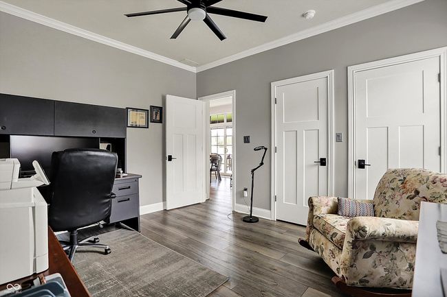 office space with ornamental molding, baseboards, a ceiling fan, and dark wood-type flooring | Image 38