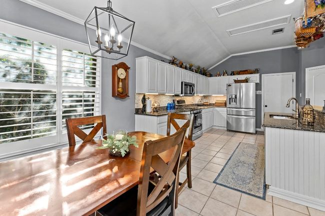 Dining space featuring lofted ceiling, sink, light tile patterned floors, ornamental molding, and a notable chandelier | Image 18