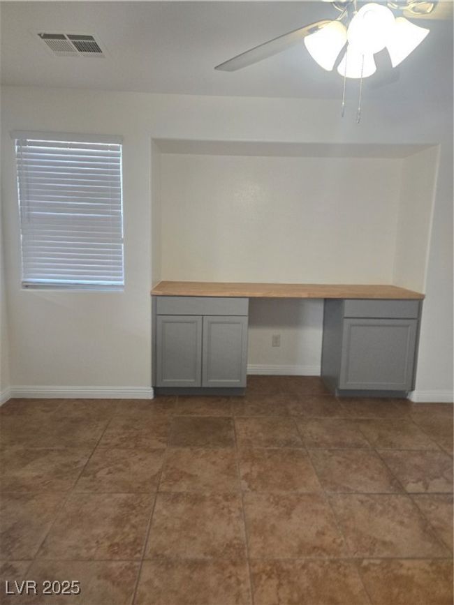Unfurnished office with built in desk, visible vents, a ceiling fan, and baseboards | Image 4