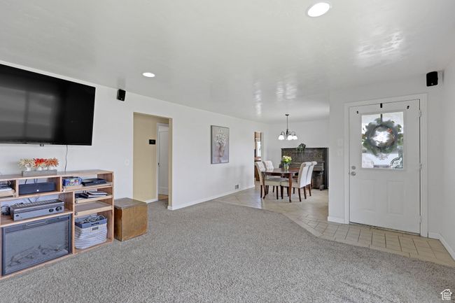 Carpeted living room with tile patterned floors, a chandelier, baseboards, and recessed lighting | Image 8