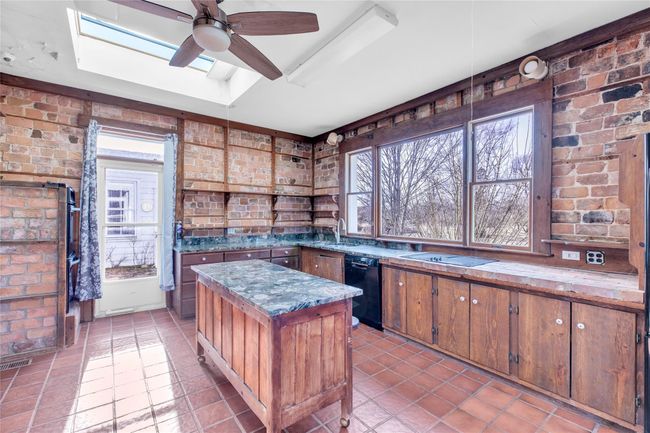 Kitchen featuring a skylight, brick wall, a kitchen island, and a tray ceiling | Image 13