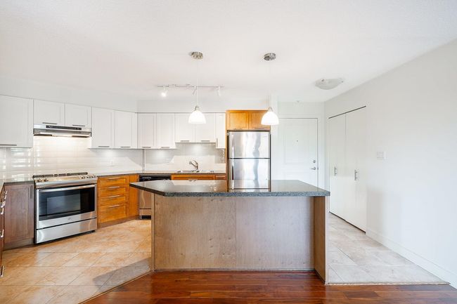 Kitchen with a sink, under cabinet range hood, decorative backsplash, a center island, and appliances with stainless steel finishes | Image 6