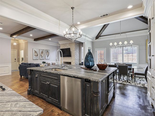Kitchen featuring a chandelier, open floor plan, dishwasher, crown molding, and a wainscoted wall | Image 8