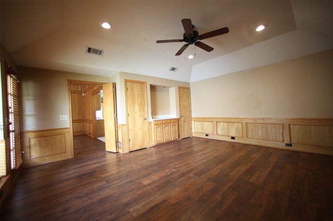 Empty room featuring vaulted ceiling, ceiling fan, dark wood finished floors, wainscoting, and recessed lighting | Image 16