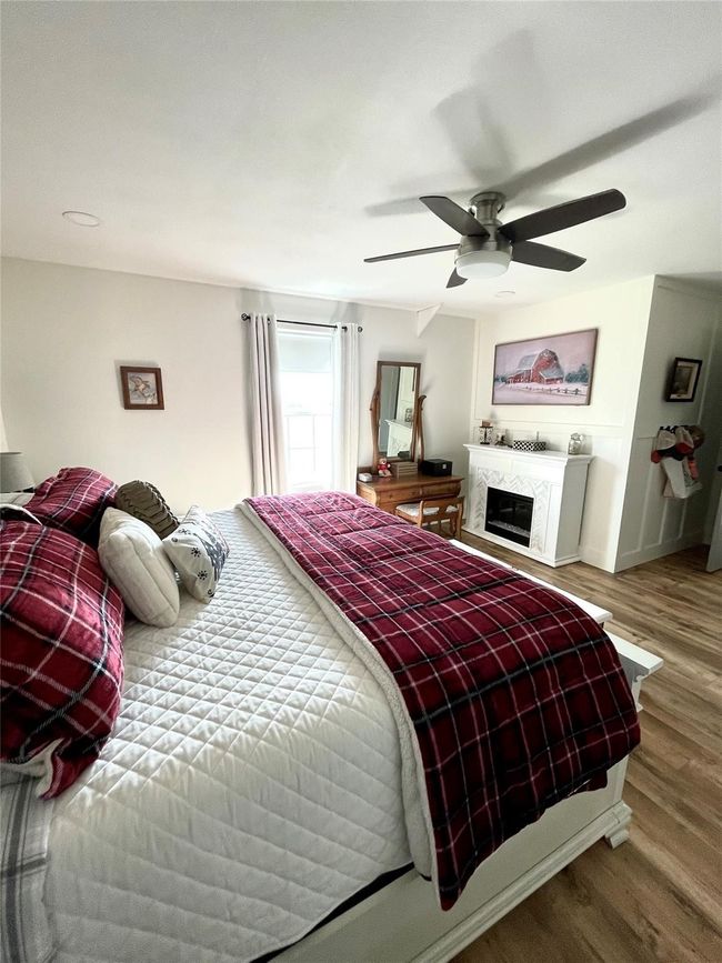 Bedroom featuring wood finished floors, a fireplace, and a ceiling fan | Image 11