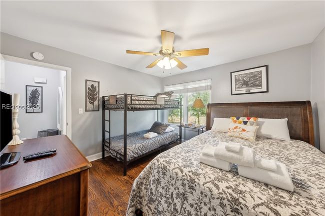 Third bedroom serves as a bunk room with a large window for beautiful natural lighting if desired, hardwood floors. Additional full size bed accomodates additonal room for sleeping. | Image 54