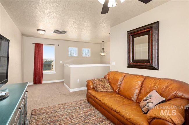 Carpeted living area with a textured ceiling and ceiling fan | Image 17