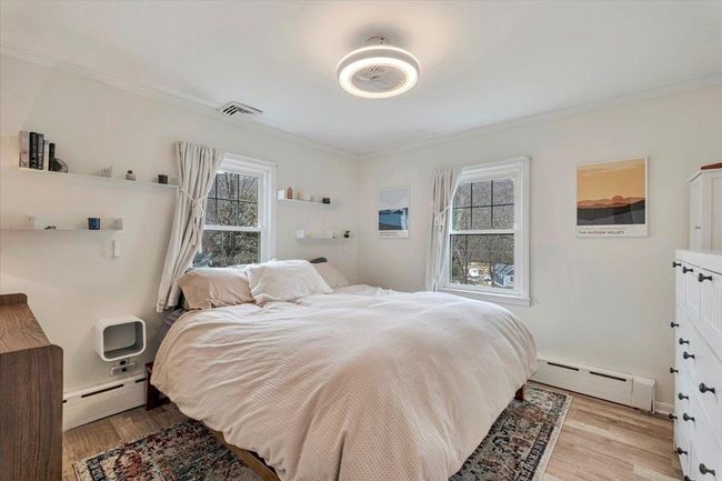 Bedroom with a baseboard radiator, light wood-style flooring, and visible vents | Image 12