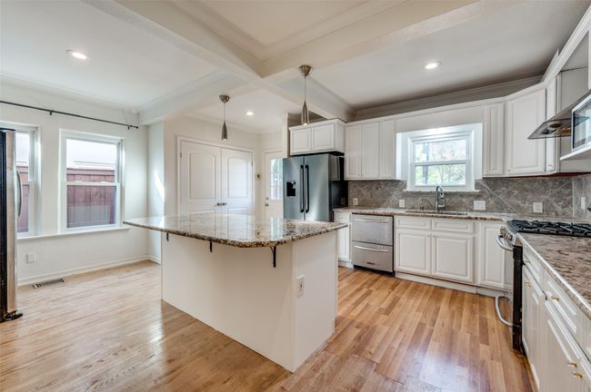 Kitchen featuring appliances with stainless steel finishes, a sink, ornamental molding, light wood-style floors, and beam ceiling | Image 13
