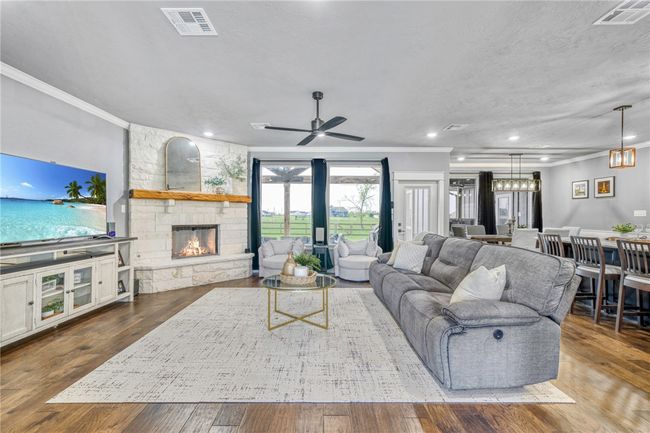 Living room with hardwood / wood-style flooring, a fireplace, ornamental molding, and a textured ceiling | Image 11