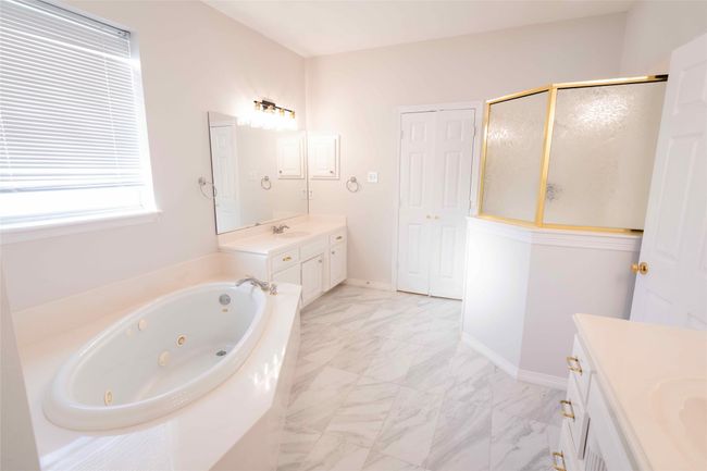 Full bathroom with vanity, a whirlpool tub, a stall shower, and marble look tile flooring | Image 17
