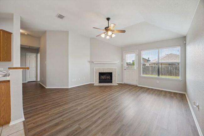 Unfurnished living room featuring ceiling fan, lofted ceiling, light wood-type flooring, a fireplace, and baseboards | Image 7