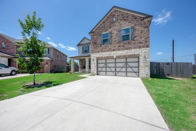 Traditional-style house with stone siding, a garage, concrete driveway, and brick siding | Image 6