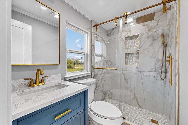 Bathroom with a marble finish shower, toilet, vanity, and ornamental molding | Image 20