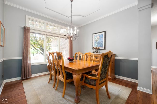 dining room with hardwood / wood-style floors, ornamental molding, and a chandelier | Image 8
