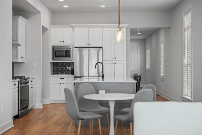 Kitchen offers eat-at island, stainless steel appliances, upgraded lighting, recessed lighting, LVP flooring. Open concept to dining area and great room | Image 8
