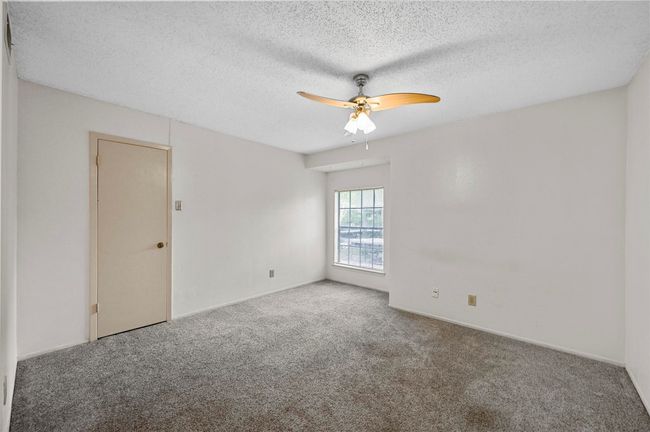 Carpeted empty room featuring a ceiling fan and a textured ceiling | Image 9