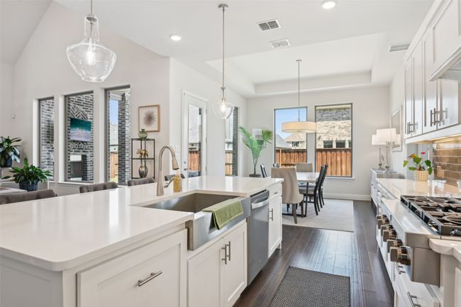 Kitchen featuring appliances with stainless steel finishes, dark wood-style flooring, a tray ceiling, recessed lighting, and white cabinets | Image 14