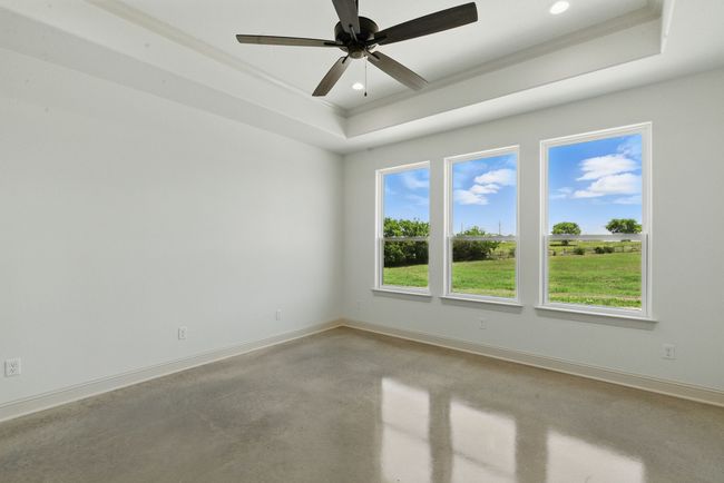 Unfurnished room with concrete flooring, crown molding, baseboards, a raised ceiling, and a ceiling fan | Image 9