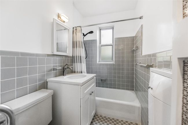 Bathroom featuring vanity, tile walls, shower / bath combo, and wainscoting | Image 18
