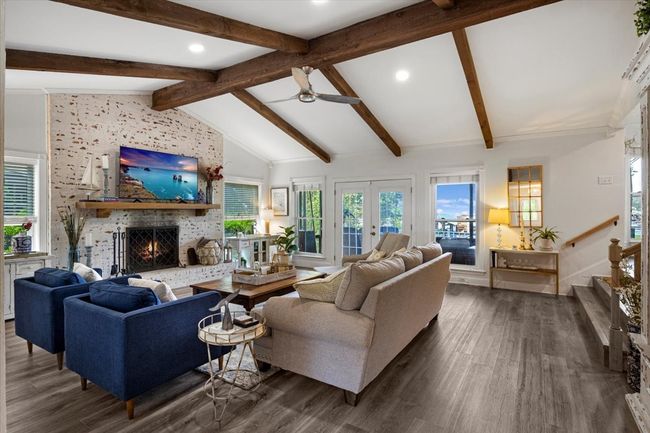 Living area with a fireplace, ceiling fan, lofted ceiling with beams, and dark wood finished floors | Image 6