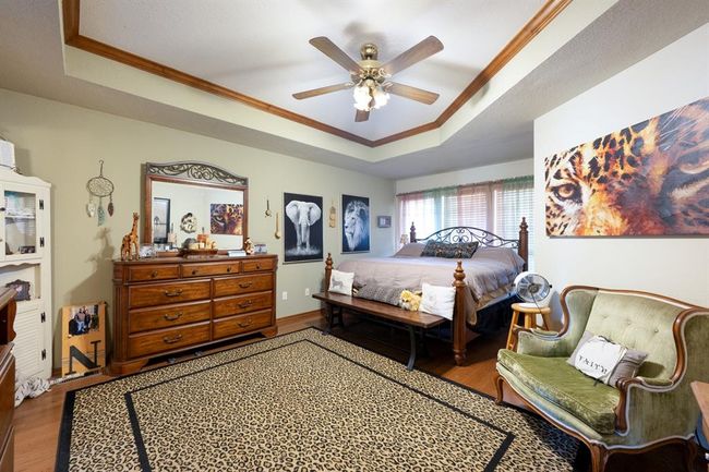 Bedroom with a tray ceiling, wood finished floors, and ornamental molding | Image 16