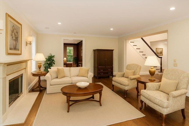 Living area featuring wood finished floors, a fireplace, stairs, recessed lighting, and ornamental molding | Image 4