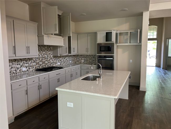 Kitchen with stainless steel appliances, a sink, dark wood-style floors, and decorative backsplash | Image 17