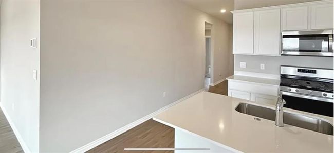 Kitchen with recessed lighting, light wood finished floors, light countertops, white cabinets, and appliances with stainless steel finishes | Image 7