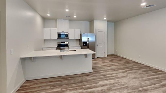 Kitchen with a breakfast bar, visible vents, stainless steel appliances, and light countertops | Image 7