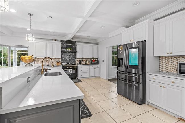 Kitchen with appliances with stainless steel finishes, a sink, tasteful backsplash, light tile patterned floors, and recessed lighting | Image 7
