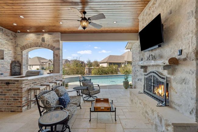 The Back Covered Patio is complete with an Alfresco kitchen, a fireplace, and two wall-mounted televisions, a 55" screen over the fireplace with asoundbar amplifier, and a 40" screen in the kitchen area. | Image 36