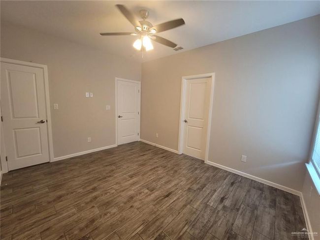 Unfurnished bedroom with dark wood-style flooring, baseboards, and a ceiling fan | Image 6