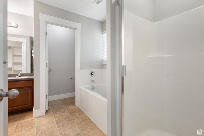 Bathroom with a bath, vanity, a stall shower, and stone finish flooring | Image 15